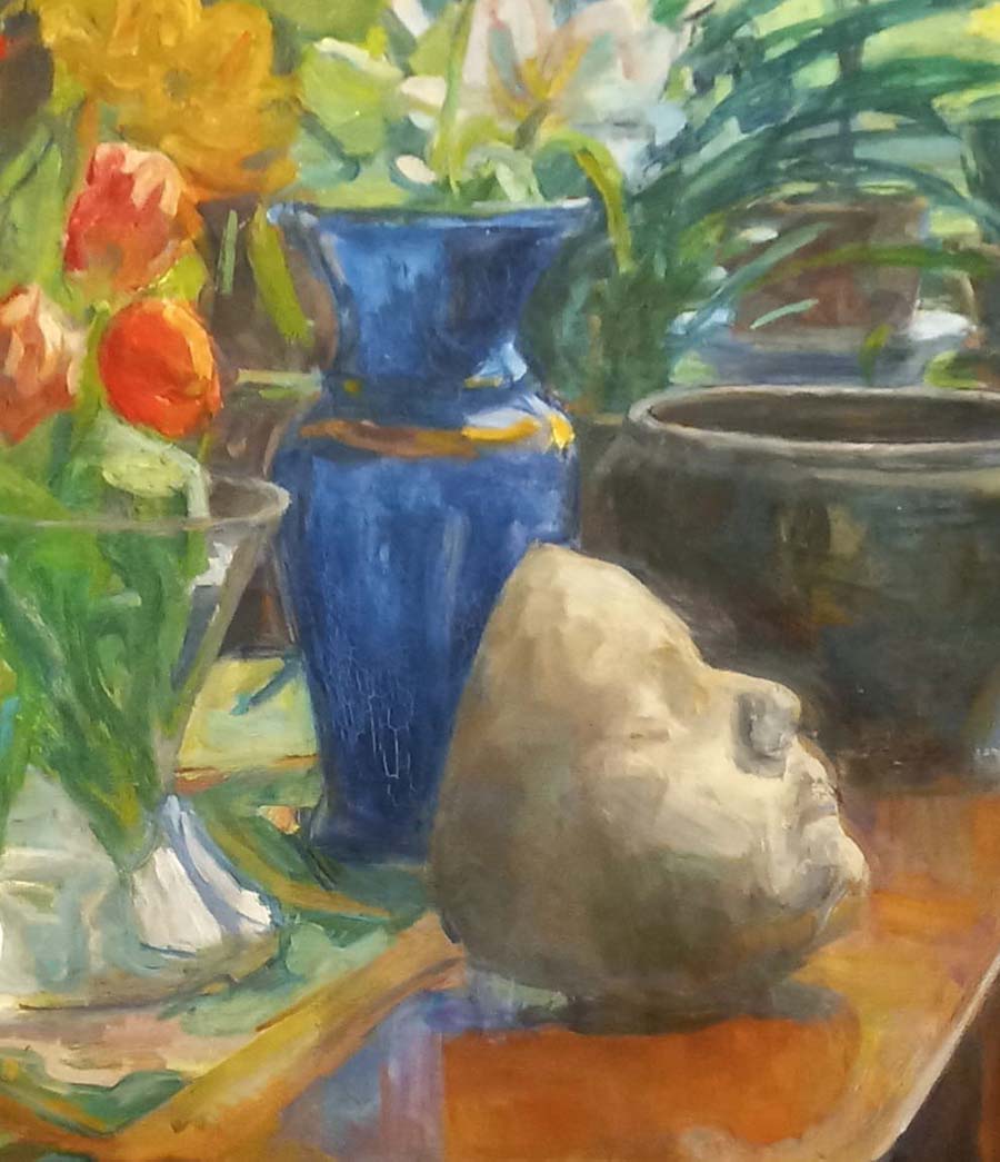 masque en plâtre posé sur une commode à côté d'un bouquet de tulipes orangé